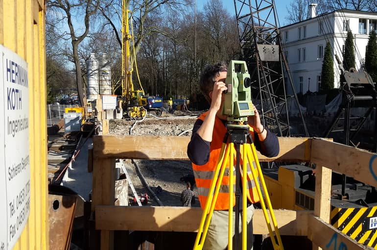Vermesser bei der Arbeit an seinem Instrument auf einer Baustelle